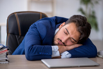 Young male employee extremely tired in the office