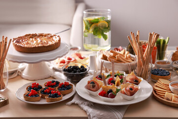 Dishes with different food on table in living room. Luxury brunch