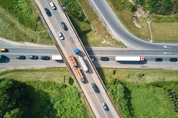 Aerial view of road intersection with fast moving heavy traffic on city streets. Uban transportation during rush hour with many cars and trucks - Powered by Adobe