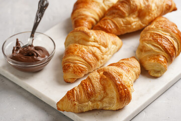 several freshly baked french butter croissants on marble tray with hazelnut spread