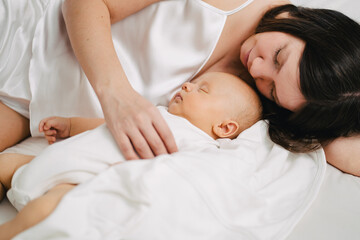 Fototapeta na wymiar mom in bed next to a sleeping baby. the happiness of motherhood. 