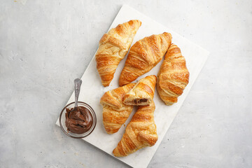 several freshly baked french butter croissants on marble tray with hazelnut spread, top view