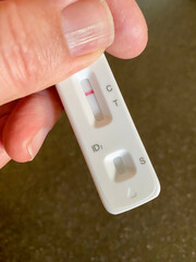 Hand holding a negative lateral flow test.