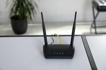 Modern Wi-Fi router on white table indoors