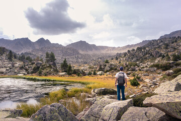 Fototapeta na wymiar Man enjoying a natural mountain landscape in the Pyrenees, Andorra, Estany Pessons