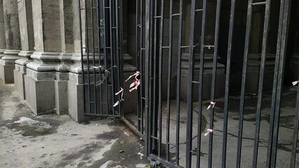 iron gate with torn and warning red and white tapes - Powered by Adobe