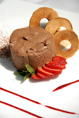 chocolate ice cream accompanied by strawberries, cookie rings and strawberry jam