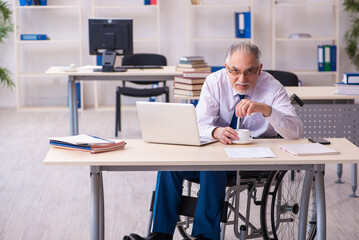 Old male employee in wheel-chair drinking coffee during break