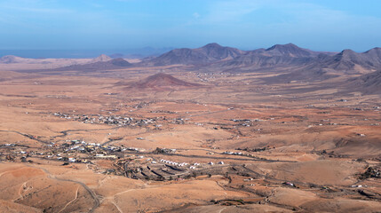 Fototapeta na wymiar Desert and volcano landscape with small towns and the sea at the background, dry landscape in Fuerteventura, Canary Islands, Spain