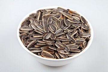 Black sunflower seeds in a bowl on white background