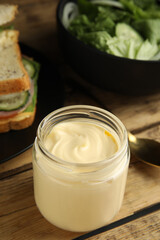 Obraz na płótnie Canvas Jar of delicious mayonnaise near fresh sandwiches on wooden table