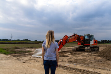 Frau schaut auf Bagger auf Feld