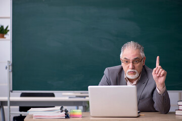Old male teacher in front of blackboard in telestudy concept