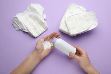 Woman applying dusting powder on violet background, top view