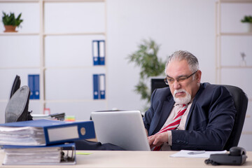 Fototapeta na wymiar Old male employee sitting at workplace
