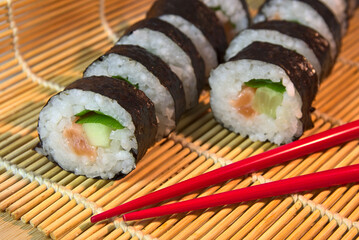 
Sushi rings on a bamboo mat with red chopsticks. Japanese cuisine.