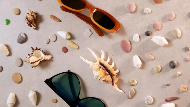 Summertime, vacation, travel and tourism concept - sunglasses and seashell lie on beach sand. Travel summer accessories with copy space, flat lay. Travel planning concept. Rotate