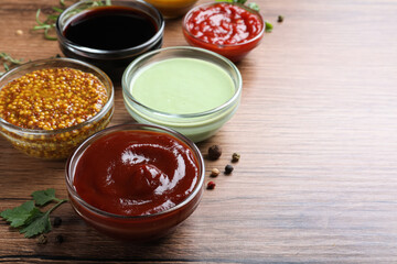 Many different sauces on wooden table, space for text