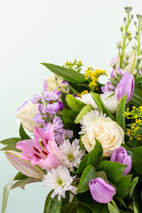 Closeup flowers background - blank greeting card or invitation with rose flowers, tulips and lily in pink and purple colors, copy space.