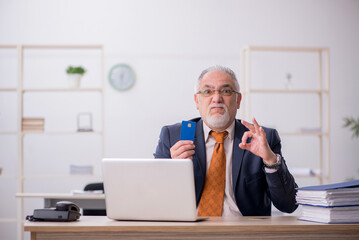 Old male employee holding credit card in the office