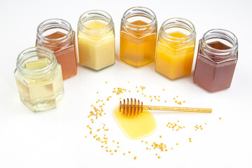 spoon with fresh honey and pollen on the background of jars with different types of honey. organic vitamin food