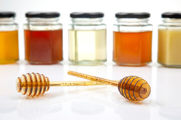 spoon with fresh honey and jars with different types of honey on a white background. organic vitamin food