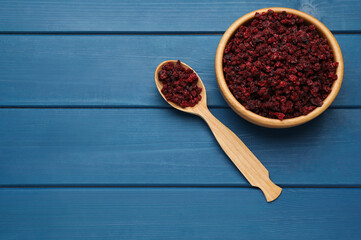 Dried red currant berries on blue wooden table, flat lay. Space for text