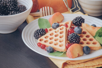 Homemade Belgian waffles served with fresh berries on white plate over wooden background, close up. Top view. Flat lay,