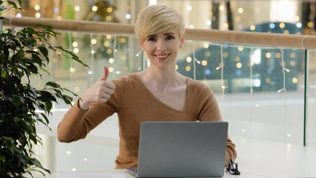 Caucasian business woman adult 40s manager freelancer using laptop free wifi typing working online net showing thumb up gesture satisfied with computer app advertising recommendation website service