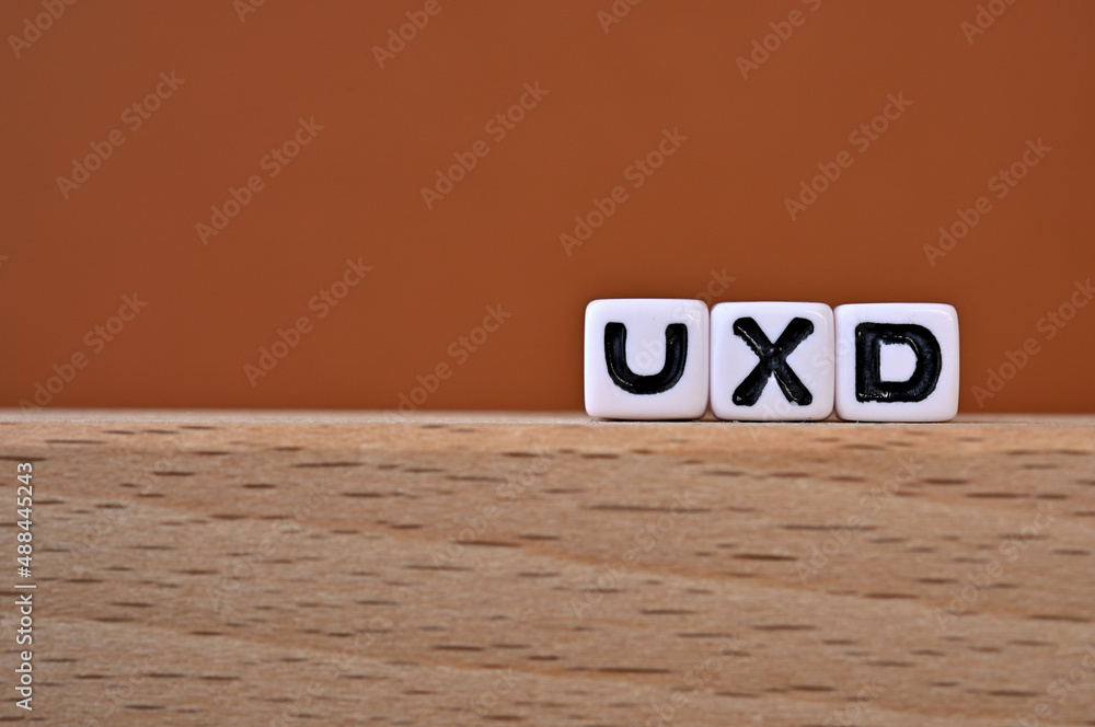 Poster word cubes lined up with the letters uxd written on it. it is an abbreviation for user experience de