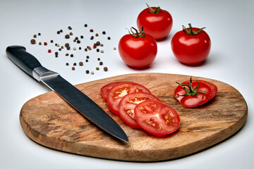 Slices of ripe tomatoes on a cutting board with a knife