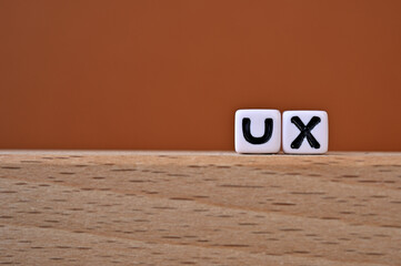 Word cubes lined up with the letters UX written on it. It is an abbreviation for User eXperience....