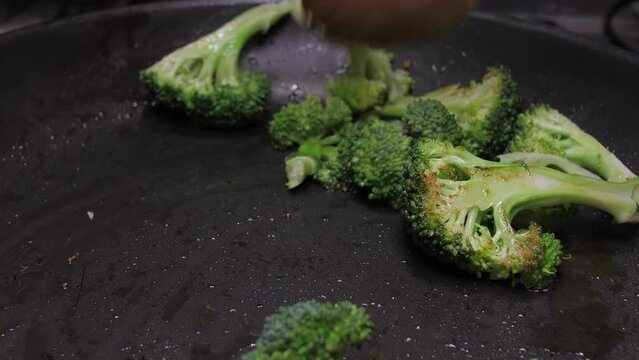 mixing broccoli with wood spoon on oil fry pan slow motion 4k