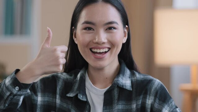 Cheerful successful asian korean positive woman girl female dental service client smiling toothy smile showing thumbs up indoors in dentist clinic good idea gesture advertisment sign agree feedback