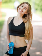 Young sporty woman with fitness beverage bottle