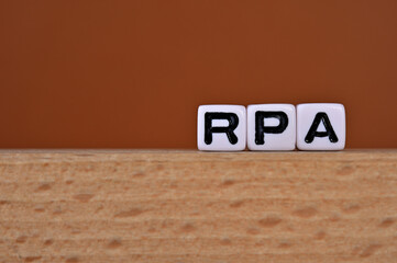 Word cubes lined up with the letters RPA written on it. It is an abbreviation for Robotic Process...