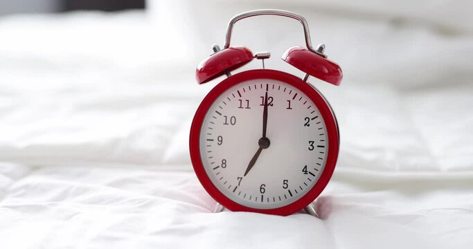 Red alarm clock for seven in morning is on bed in bedroom