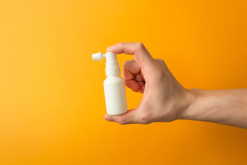 Man's hand holds a white ear spray bottle. For daily clean the ears from earwax. Health care...