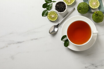 Cup of tasty bergamot tea, dry leaves and fresh fruits on white table, flat lay. Space for text