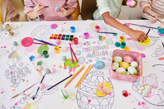 Background image of children painting Easter eggs and coloring books while enjoying art and craft class together
