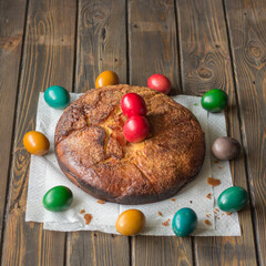 Kozunak (Traditional Easter homemade sweet bulgarian bread) and a circle colored eggs on a table of wooden planks