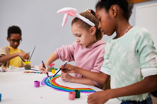 Portrait of two little girls drawing rainbow at art and craft table while enjoying Easter party for children - Powered by Adobe