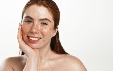 Face of smiling redhead woman plus size, touching clean healthy facial skin after cleansing skincare products and cosmetic procedure, looking happy, white background