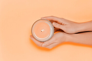 Female hands with scented candle and flowers. Aromatherapy and spa