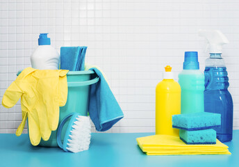 Set of cleaners and detergents, cleaning accessories, blue background with tiles. Concept spring...