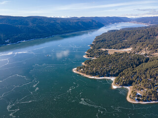 Fototapeta premium Aerial winter view of Dospat Reservoir covered with ice, Bulgaria