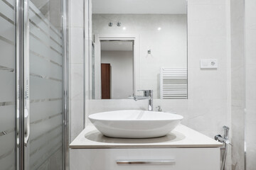 Fototapeta na wymiar Shell-shaped white porcelain washbasin with shower tray, square wall mirror and white aluminum beam