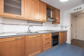 full kitchen with white wood countertops with cherry cabinets and stainless steel appliances in a vacation rental apartment