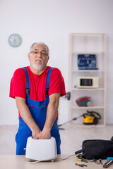Obraz premium Old repairman repairing toaster at workshop