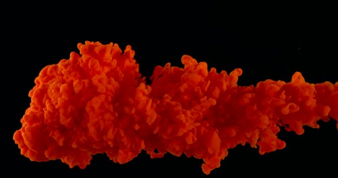 A cloud of red ink or paints in water on a black isolated background.